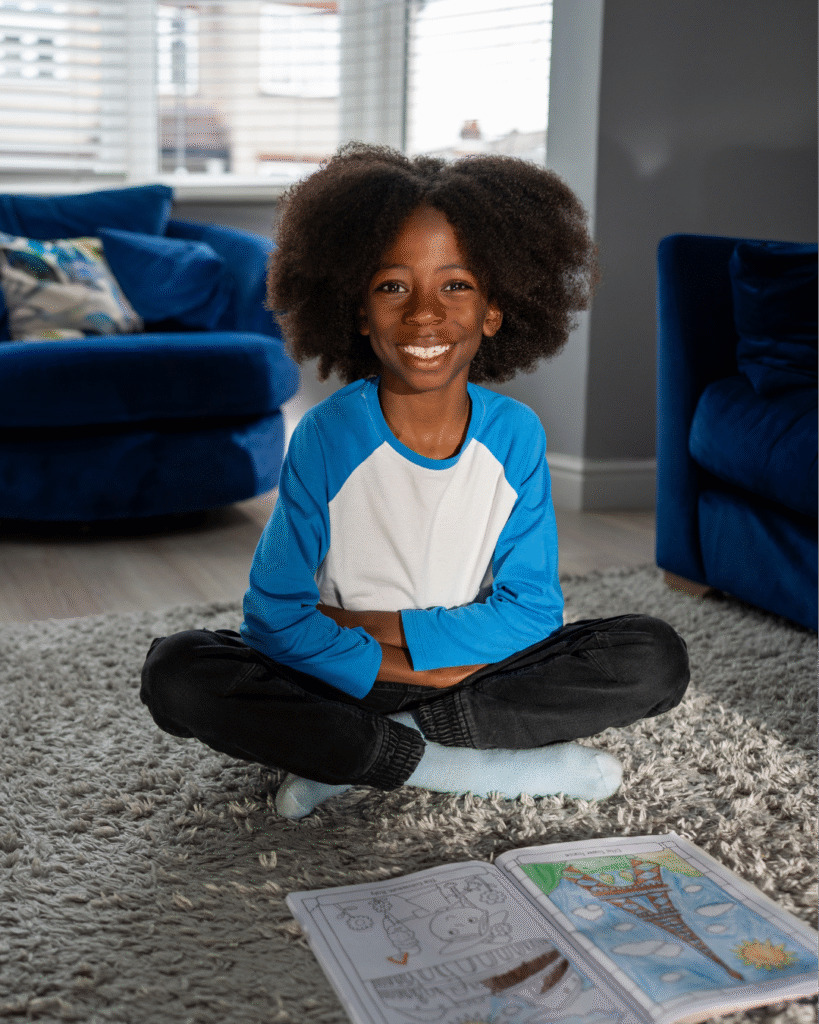 Photo of 9 year old Tyrae smiling and sitting on the floor